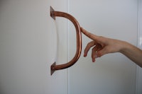 a person's hand reaching for a handle on a wall